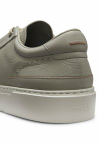 Light gray leather sneaker with a textured finish, padded collar, and contrasting stitching. Features a raised brand logo on a white sole.