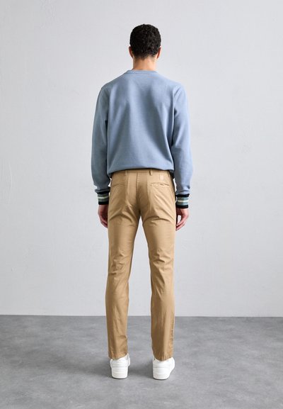 Light blue sweatshirt with striped cuffs, tan trousers, and white sneakers. Smooth texture, casual design, and fitted silhouette.