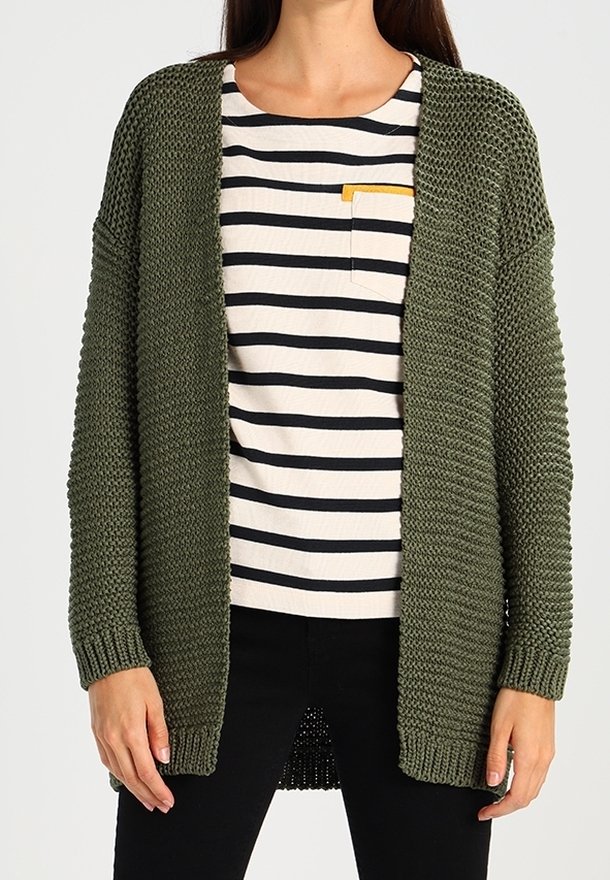 Cárdigan de punto verde oliva con frente abierto, tejido texturizado y mangas largas, usado sobre una camisa a rayas con un bolsillo amarillo.