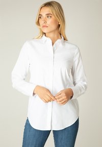 Witte lange mouw blouse met een kraag, met een rechte zoom en gladde katoenstof, gecombineerd met blauwe jeans.