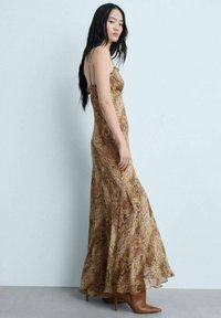 Abito maxi in un motivo ondulato marrone e beige, realizzato in tessuto leggero con un corpetto aderente e una gonna fluente, dotato di spalline sottili.