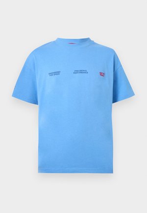 Világoskék rövid ujjú póló kerek nyakkivágással, kis fekete feliratokkal: "Engineered for Speed" és "Precision & Performance", valamint piros felirattal: "On the Track".