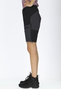 Svarta och grå shorts med en dragkedjeficka, lätta material, åtsittande design och knälång klipp, i kombination med svarta vandringsskor.