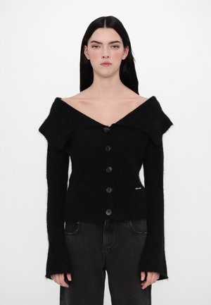 Cardigan negru tricotat cu design off-shoulder, guler supradimensionat și șase butoane mari. Are mâneci lungi cu manșete evazate.
