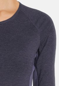 Maglietta a maniche lunghe blu navy con tessuto a maglia testurizzato. Presenta maniche raglan e un collo liscio. Unisce design aderente e comfort.