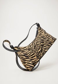 Black and beige tiger-striped handbag made of textured material, featuring a curved design and a black adjustable strap.