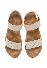 Sandali beige chiaro con una fascia intrecciata e ondulata sopra le dita e una ampia fascia elastica intorno alla caviglia su una suola morbida e tessurizzata.