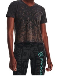 Camiseta negra corta con un diseño en degradado, que presenta un gran logo negro. Combinada con leggings negros que muestran varios patrones de texto en turquesa.