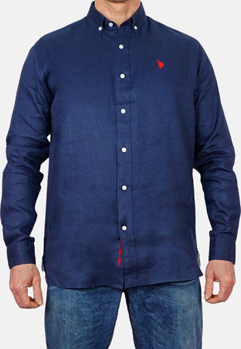 Marinblå knapplöst skjorta gjord av texturerat tyg, med en liten röd logotyp på bröstet och en röd detalj vid fållen. Långa ärmar.