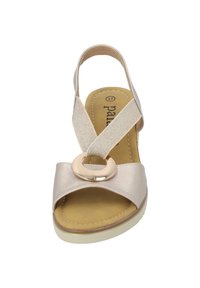 Sanda le beige in pelle con punta aperta, una larga fascia incrociata sul piede, un accento circolare dorato e una fascia per caviglia supportiva.