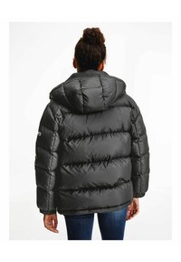 Svart pufferjacka med huva, med quiltade partier och elastiska manschetter. Materialet har en slät, glänsande yta.