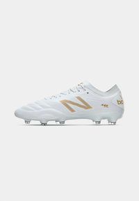 Botas de futebol brancas com detalhes em dourado, apresentando um cabedal sintético texturizado, bico arredondado e seis cravos moldados para tração.