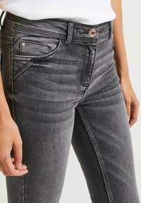 Grå denimjeans med en åtsittande design, som har en framåt mini ficka, kopparfärgad hårdvara och subtila texturlinjer.