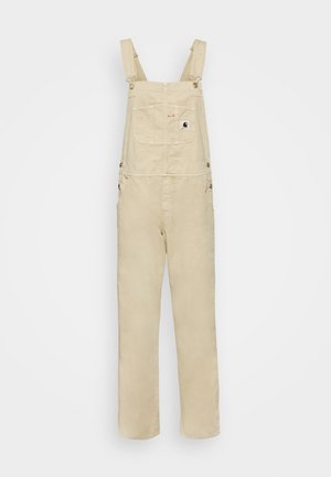 Beige cotton overalls with adjustable shoulder straps, front chest pocket, and side pockets. Smooth texture and straight leg design.