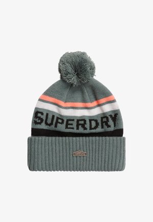 Dzianinowa czapka w kolorze teal z pomponem na czubku. Posiada poziome paski w kolorze koralowym, białym i czarnym. Wyróżniające się logo "SUPERDRY" w grubym czarnym fontzie.