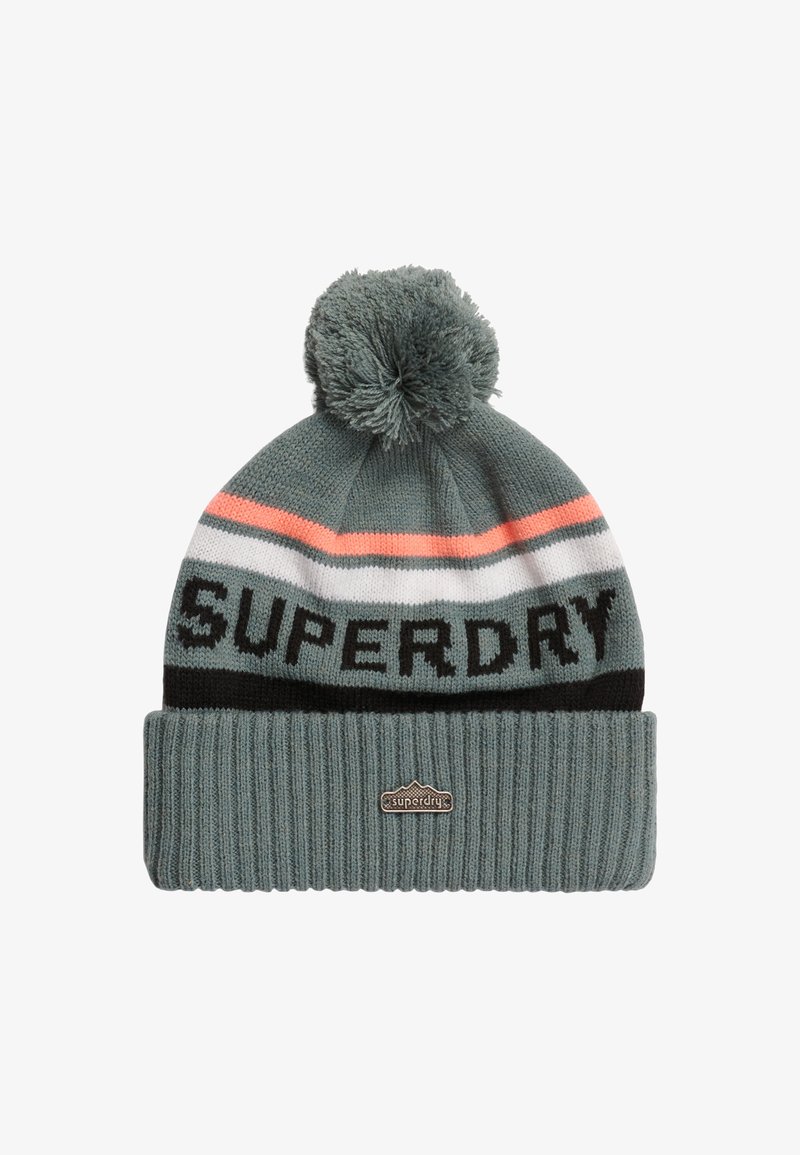 Gorro de punto en color teal con un pompón en la parte superior. Presenta rayas horizontales en coral, blanco y negro. Logo "SUPERDRY" en negrita color negro.