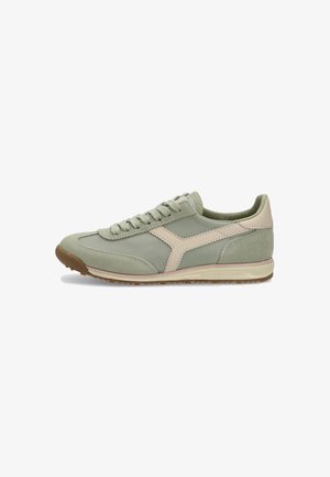 Zapatilla atlética verde claro con una mezcla de materiales superiores lisos y texturizados, que presenta un acento rosa pálido y una suela de goma marrón.