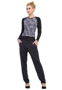 Long-sleeve top with black sleeves and a white leopard print body, paired with loose black pants featuring a folded waistband.