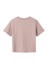 T-shirt à manches courtes, col rond en coton rose pâle. Couleur unie, simple, avec une coupe décontractée et sans logos ni motifs visibles.