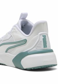 Baskets Puma blanches et turquoise avec semelle texturée, panneaux latéraux en mesh, col rembourré et logo Puma sur le talon et le côté.