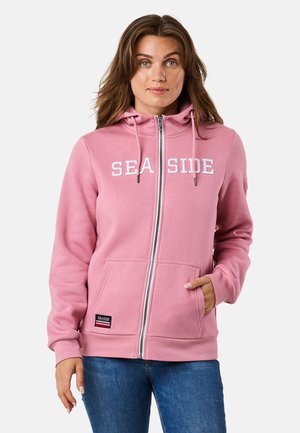 Różowa bluza z kapturem na zamek, z przednią kieszenią typu kangur, z napisem "SEA SIDE" w białym kolorze na wysokości klatki piersiowej oraz regulowanymi sznurkami w kapturze.