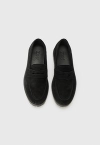 Zwarte suède loafers met een platte zool, voorzien van een decoratieve band en een gladde textuur. Rond dorsontwerp, minimale branding aan de binnenkant.