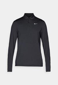 Camisa polo negra de manga larga hecha de tela suave, con un cuello clásico y un logotipo blanco de Nike en el lado izquierdo del pecho.