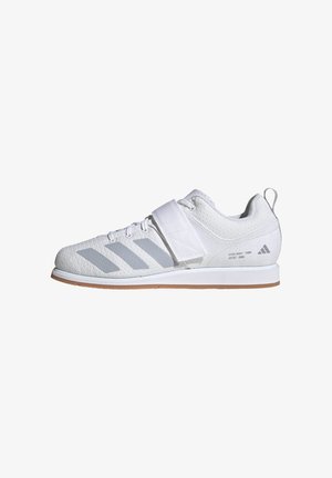 Valkoinen Adidas-urheilukenkä harmailla raidoilla, edessä nauhat, tarranauhakiinnitys ja vaaleanruskea pohja, esitetty sivuprofiilissa.