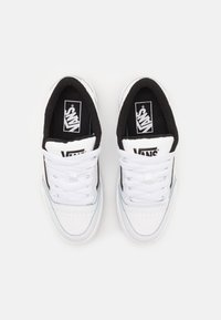 Białe sneakersy z czarnymi akcentami, górna część z gładkiego tworzywa syntetycznego, okrągły czubek i płaskie sznurówki. Posiadają wyściełany kołnierz oraz logo Vans na języku.