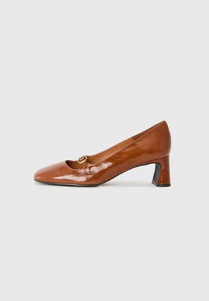 Brown patent leather high heel pump with a rounded toe, small cutout, and decorative buckle detail on the upper, set on a block heel.