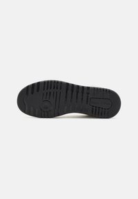 Black rubber shoe sole with a textured pattern, featuring a circular logo and the brand name "Marc O'Polo" embossed on the surface.