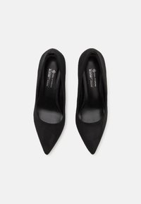 Escarpins noirs à bout pointu, fabriqués en matériau doux et texturé. Design épuré avec un intérieur lisse et une étiquette vegan à l'intérieur.