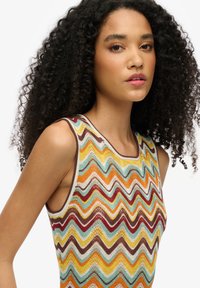 Strikket tanktop med zigzag-mønster i livlige farver: orange, gul, turkis, rød og brun. Ærmeløs design med rund halsudskæring.