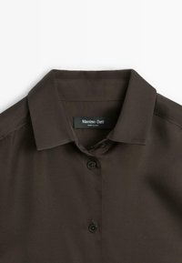 Dunkelbraunes Hemd mit Kragen und Knopfverschluss, aus glattem Stoff. Bietet ein Etikett: "Massimo Dutti, MADE IN CHINA." Minimalistisches Design.