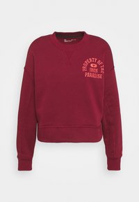 Felpa bordeaux con colletto a girocollo a coste, maniche lunghe e un taglio cropped. Presenta il testo arancione "Proprietà dell'Iron Paradise."