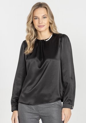 Czarna satynowa bluzka z długimi rękawami, okrągłym dekoltem i perłowym akcentem na kołnierzyku. Gładka faktura i luźny krój.
