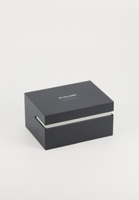 Schwarze rechteckige Box mit strukturierter Oberfläche, mit einer weißen Papierauskleidung und dem geprägten Markennamen "DI MILANO" auf dem Deckel.