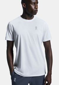 White short-sleeve athletic t-shirt made of lightweight material, featuring a subtle logo on the chest and a relaxed fit.