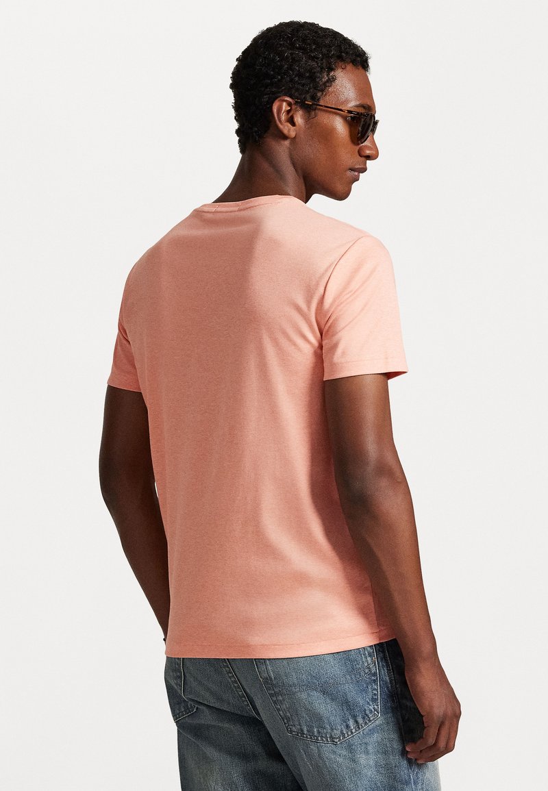 T-shirt à manches courtes, col rond en coton corail doux, avec une texture lisse et une coupe décontractée, associé à un jean bleu.