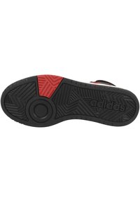 Czarna gumowa podeszwa buta z teksturowanymi wzorami, okrągłym akcentem i czerwonym segmentem. Na boku znajduje się wytłoczone logo "adidas".