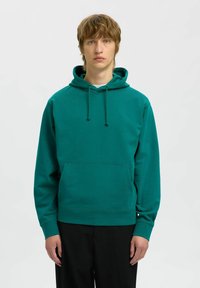 Felpa color teal con tasca a marsupio frontale, cappuccio regolabile con cordino e polsini a costine. Realizzata in un tessuto morbido con una texture liscia.