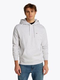 Grijze katoenen hoodie met een voorzak, verstelbare trekkoordkap en een klein logoaccent. Gecombineerd met blauwe jeans.