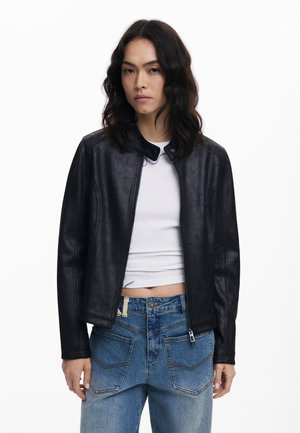 Black faux leather jacket with a stand-up collar, zip closure, and smooth texture. Paired with light blue denim jeans featuring back pockets.