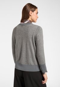 Grijze gebreide trui met geribde zoom en manchetten, met een gladde kraag, een klein logodetail op de achterkant en een zachte textuur.