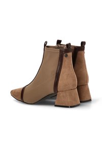 Botas de tobillo de ante marrón con puntera afilada, que presentan una combinación de materiales lisos y texturizados, y un diseño de tacón grueso.