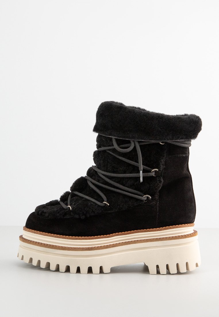 Botines de ante negro con puño de piel sintética, que presentan un diseño de cordones, suela de plataforma blanca gruesa y una textura en la suela para mayor agarre.