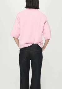 Pink knit sweater with short sleeves, round neckline, and a relaxed fit, paired with dark denim jeans featuring back pockets and a straight leg.