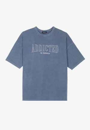 Modrá bavlněná tričko s oversized střihem. Disponuje zaobleným výstřihem a bílou grafickou hláškou: "ADDICTED TO PARADISE" ve zakřiveném provedení.