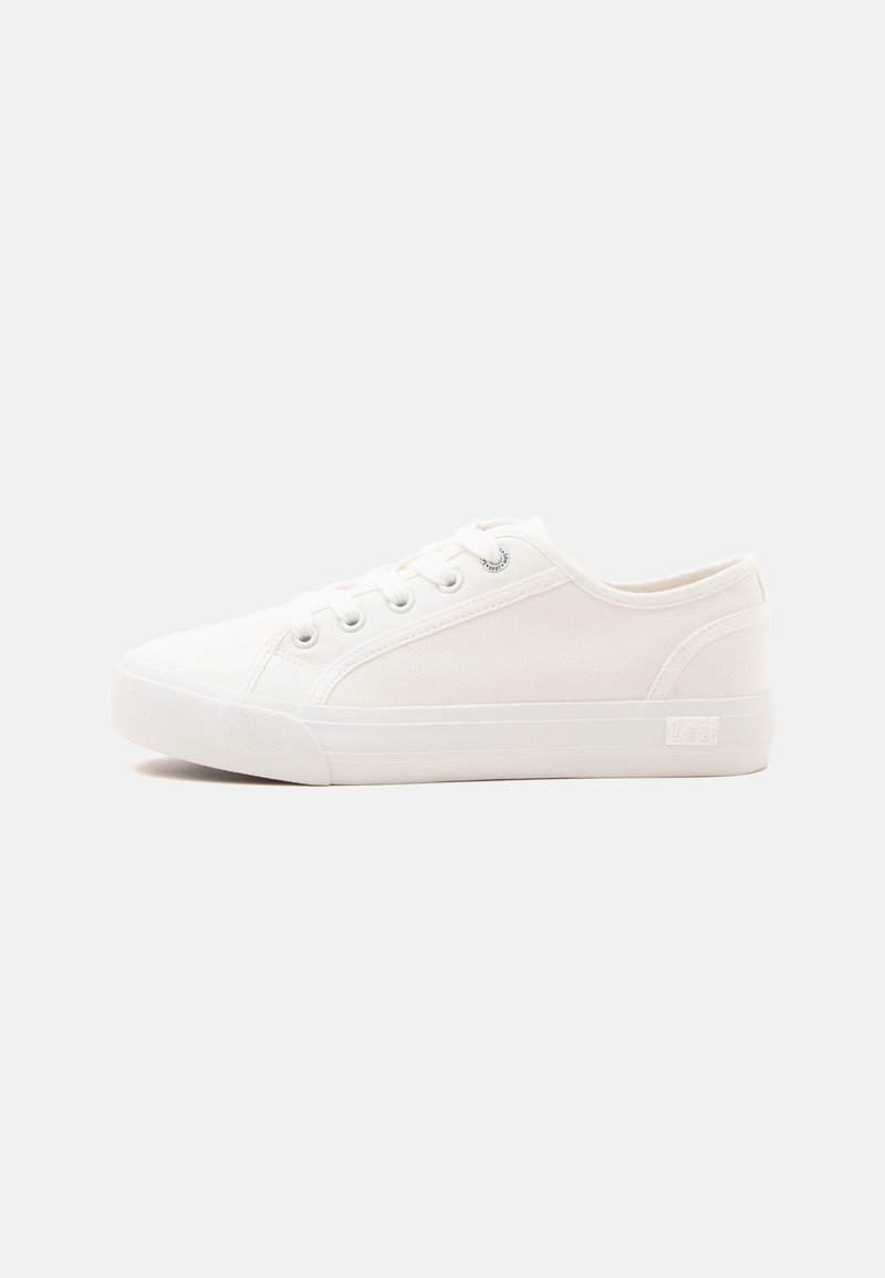 Λευκό χαμηλό καμβά sneaker με λευκή λαστιχένια σόλα και λευκά κορδόνια, παρουσιάζεται σε απλό φωτεινό φόντο.
