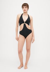 Svart badedrakt med halterneck, utskårne sider og gulldetaljer. Glatt, elastisk stoff med en elegant overflate.